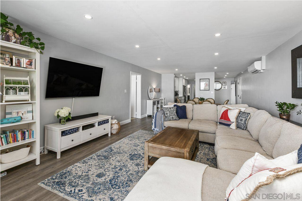 Light gray living room with sectional sofa, large TV, gray wood floor